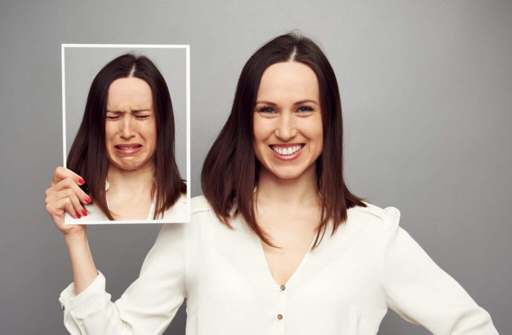 happy woman holding pic of her unhappy face